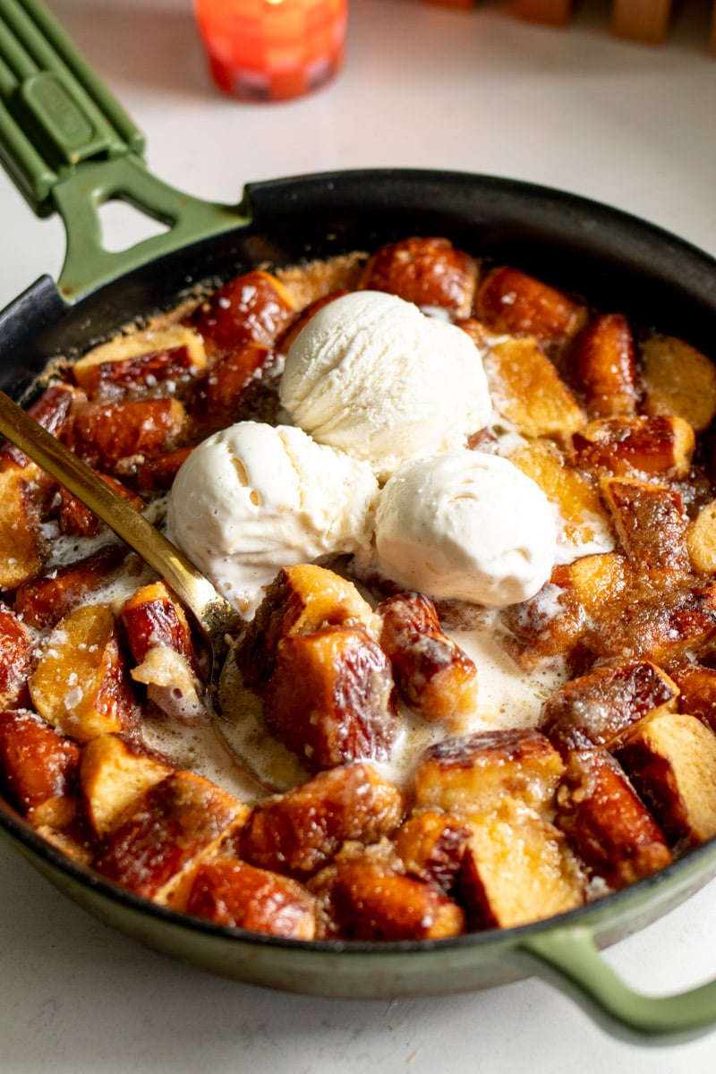 salted caramel bread pudding in a big cast iron skillet with three scoops of ice cream on top.