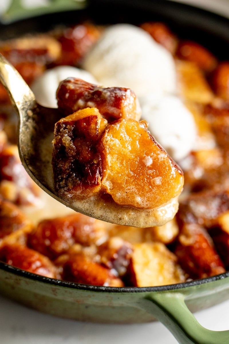 a spoon holding a scoop of vanilla ice cream and bread pudding.