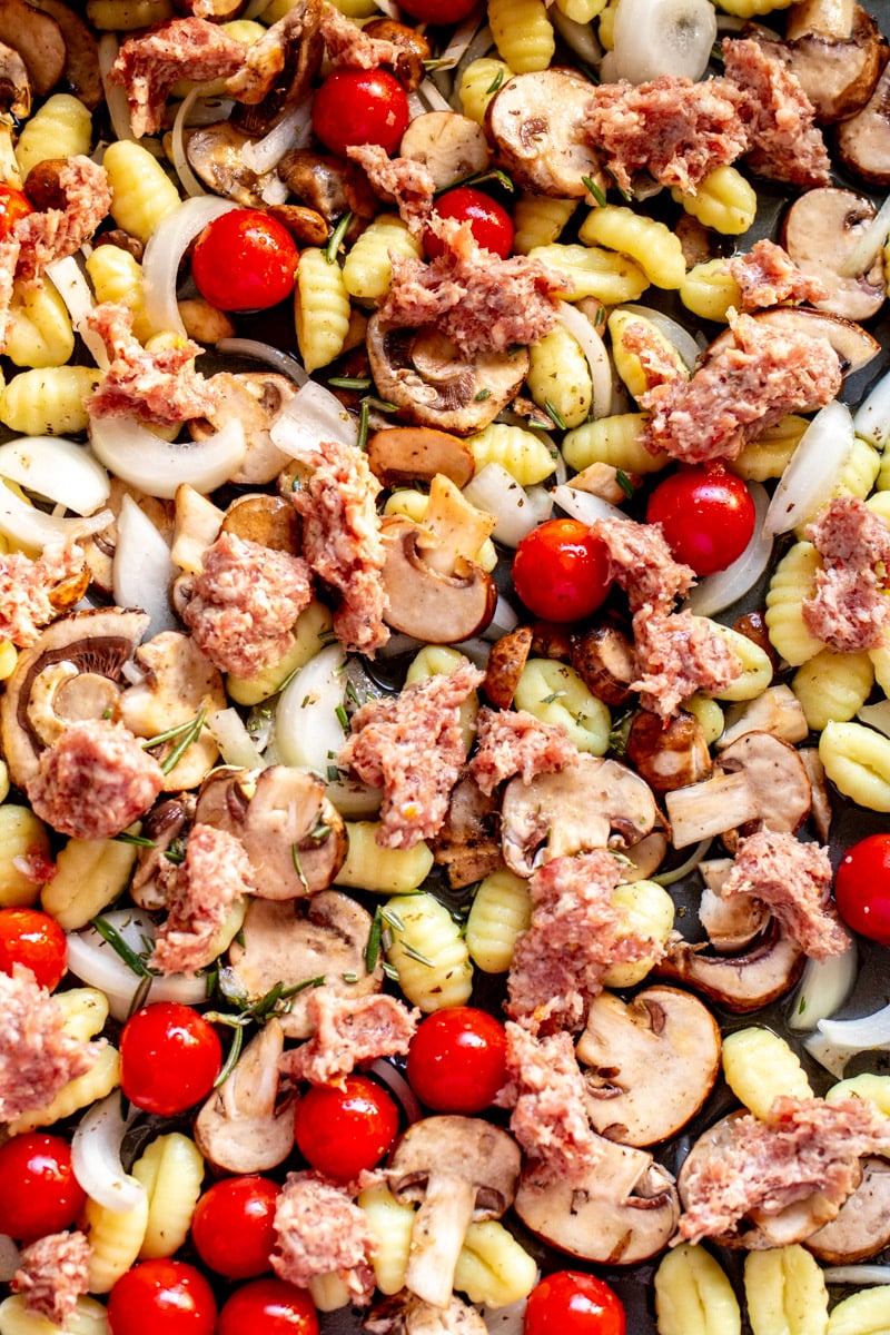 a sheet pan topped with sausage, rosemary and white wine.