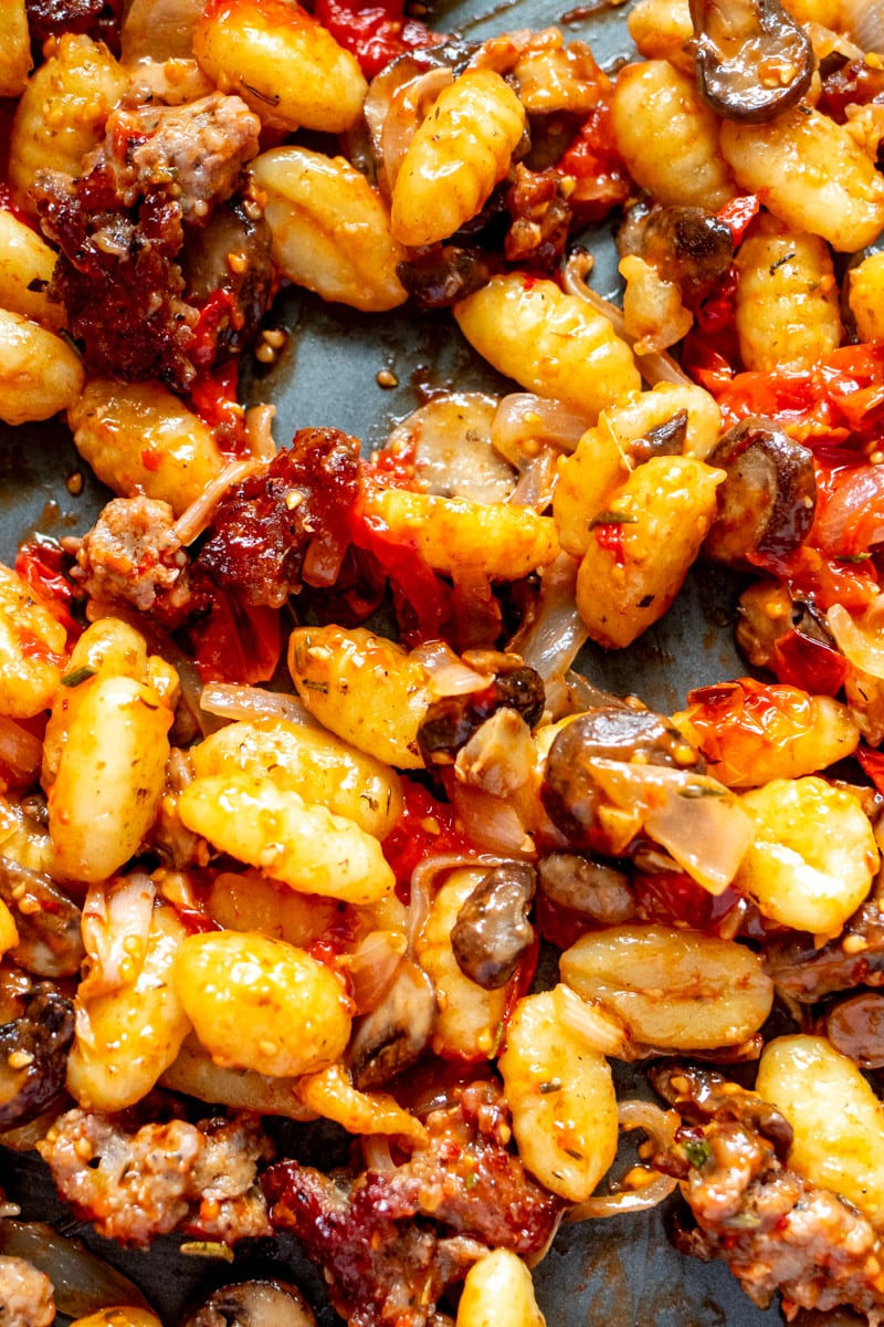 crispy crumbled sauasge on a sheet pan with vegetables and gnocchi.