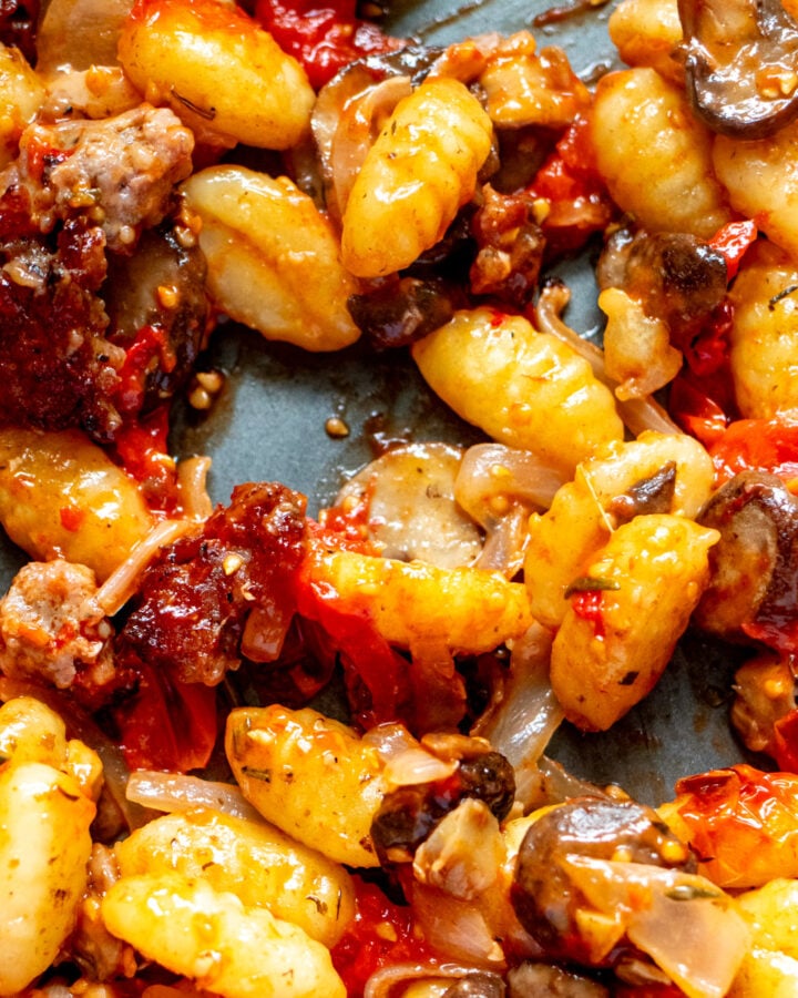 a sheet pan topped with crispy sausage, veggies and gnocchi,