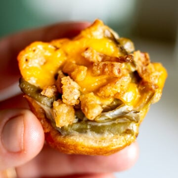 a hand holding a singular green bean casserole appetizer bite.