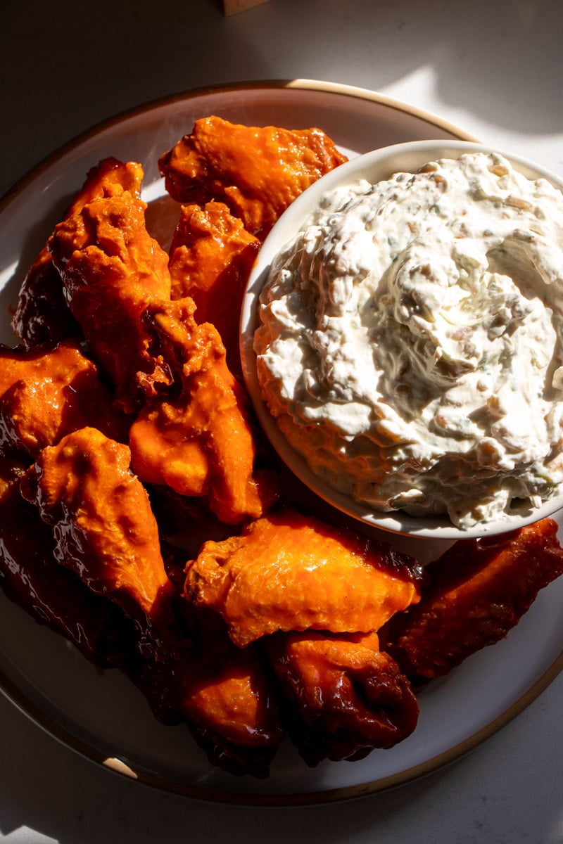 buffalo wings and caramelized onion dip on a white plate.