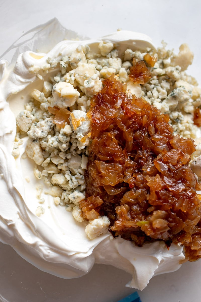 caramelized onions, blue cheese and sour cream in a glass bowl.