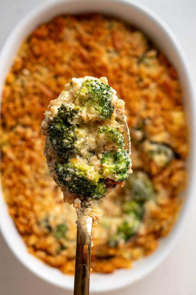 an overhead view of a spoon scooping out some broccoli cheese casserole.