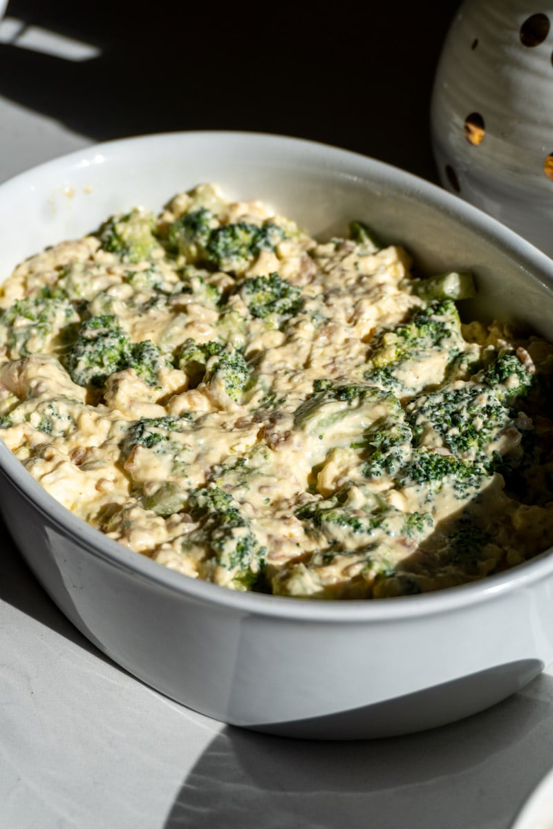 all the ingredients in cheesy broccoli casserole in a white baking dish.