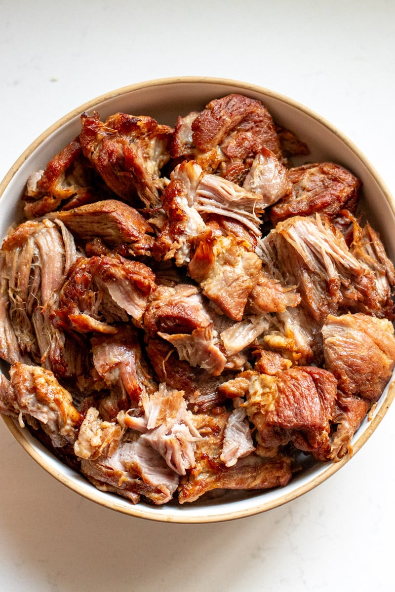 an overhead view of a white bowl filled with crispy slow cooker pulled pork.