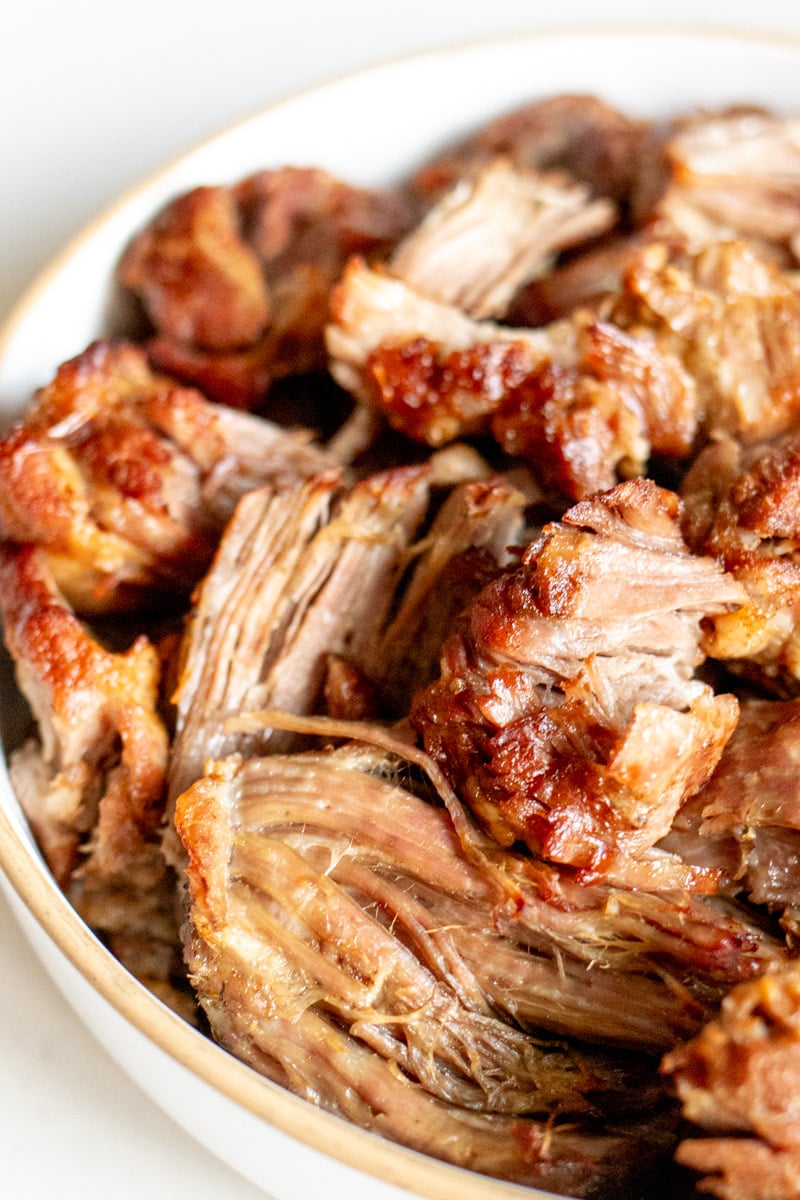 an up close view of the left side of a platter of golden brown pulled pork.