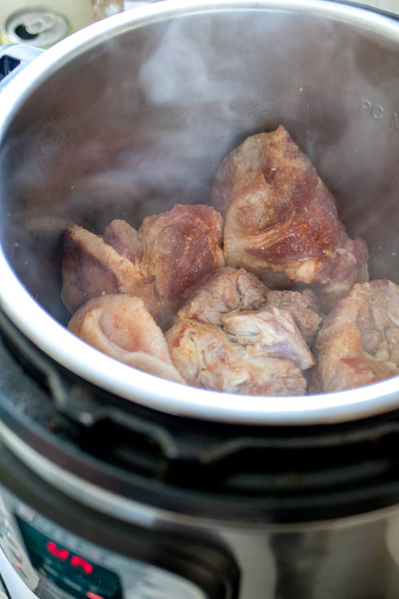 pieces of pulled pork in a pressure cooker browning.