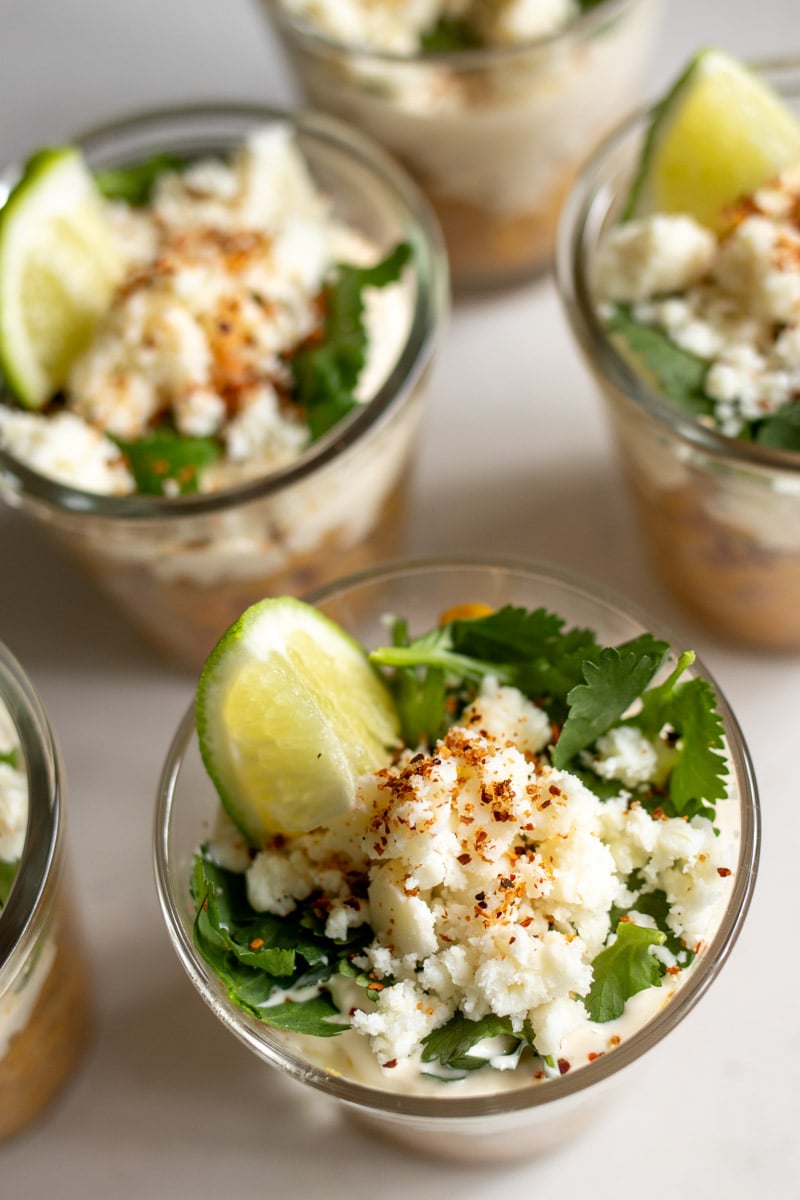 an semi overhead view of elote in a cup on a white countertop.