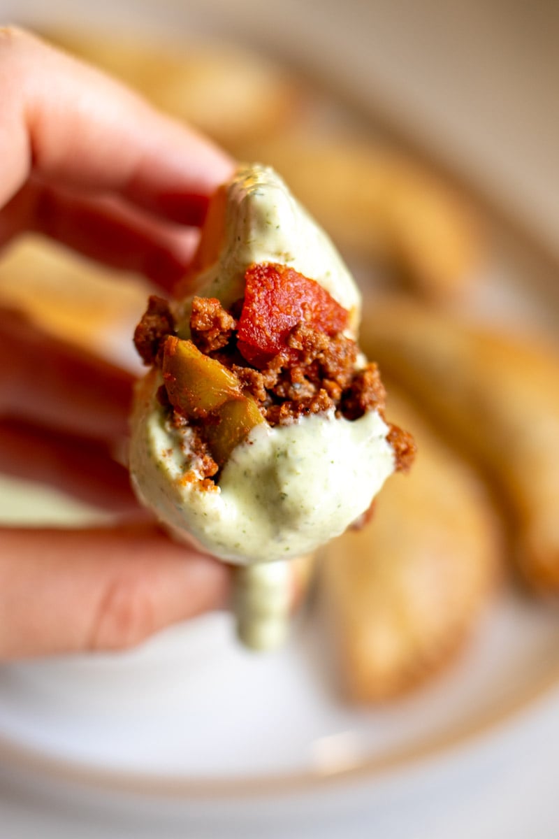 a empanada split in half showing the inside which is ground beef with tomatoes and olives. 