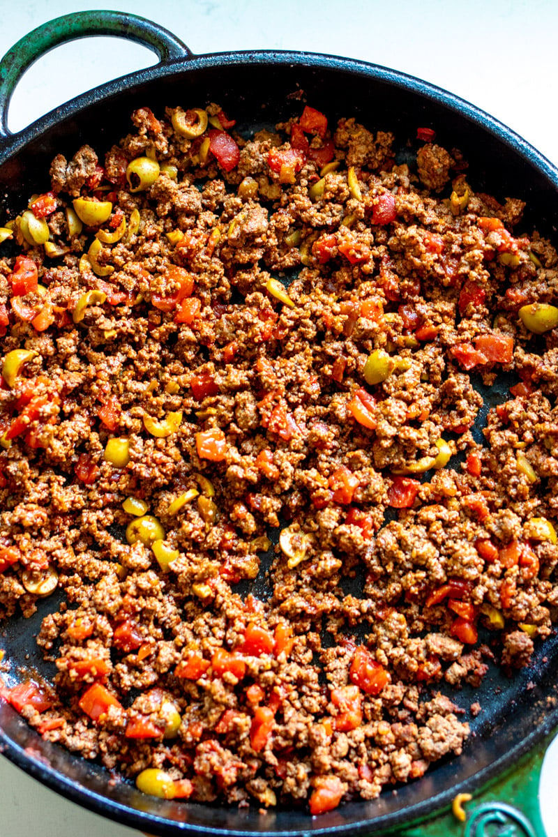 ground beef cooking in a large cast iron fry pan.