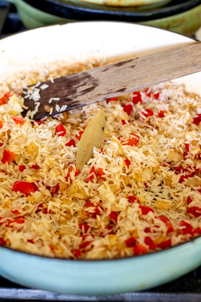 rice, onions, peppers and spices in a pot.