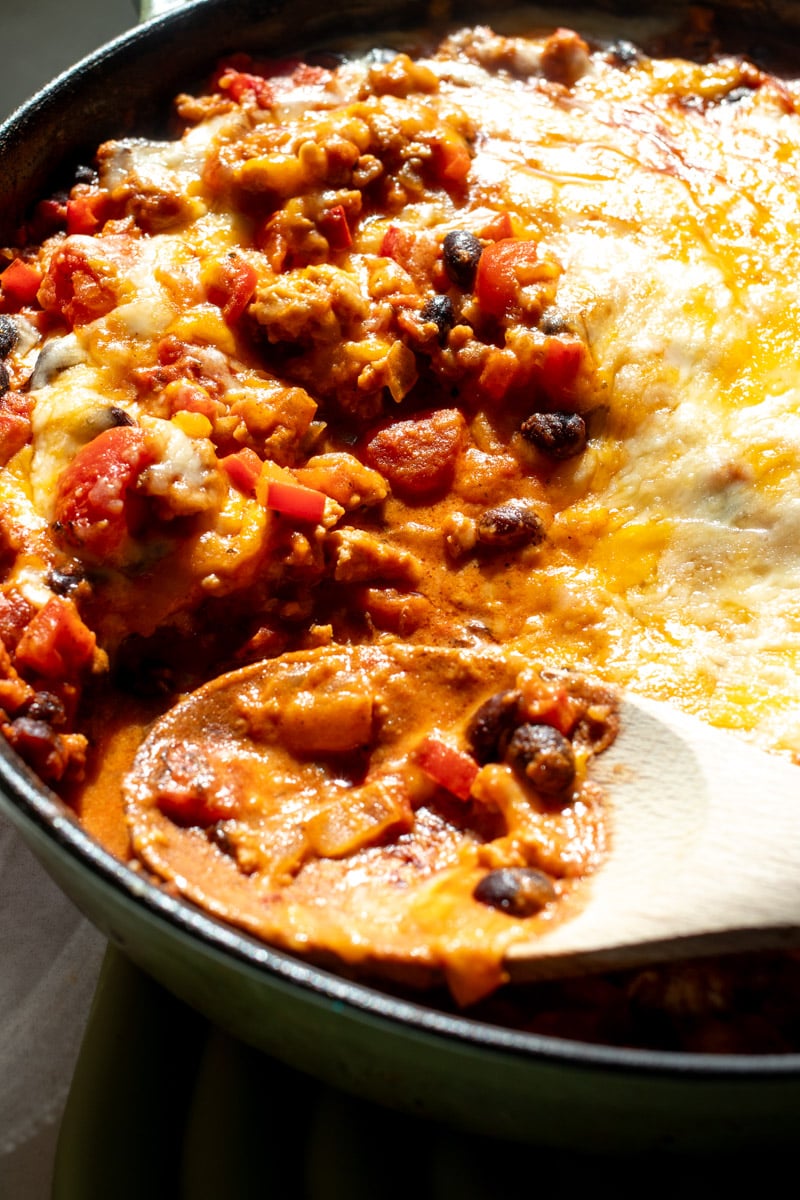 a spoon sitting on top of a cheesy chicken chipotle skillet.