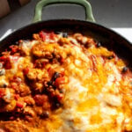 a green skillet full of cheesy chipotle chicken, beans, spicy sauce and lots of melted cheese.