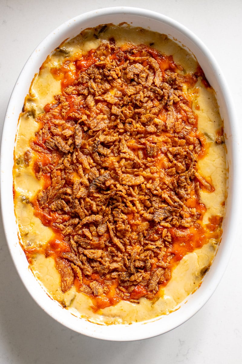 baked cheesy green bean casserole in a white casserole dish.