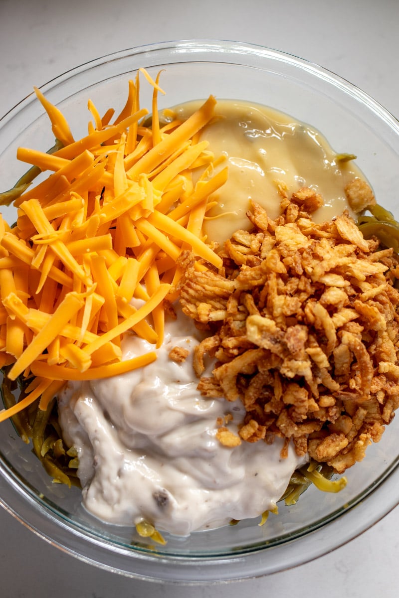 ingredients for green bean casserole mixed together in a glass bowl.