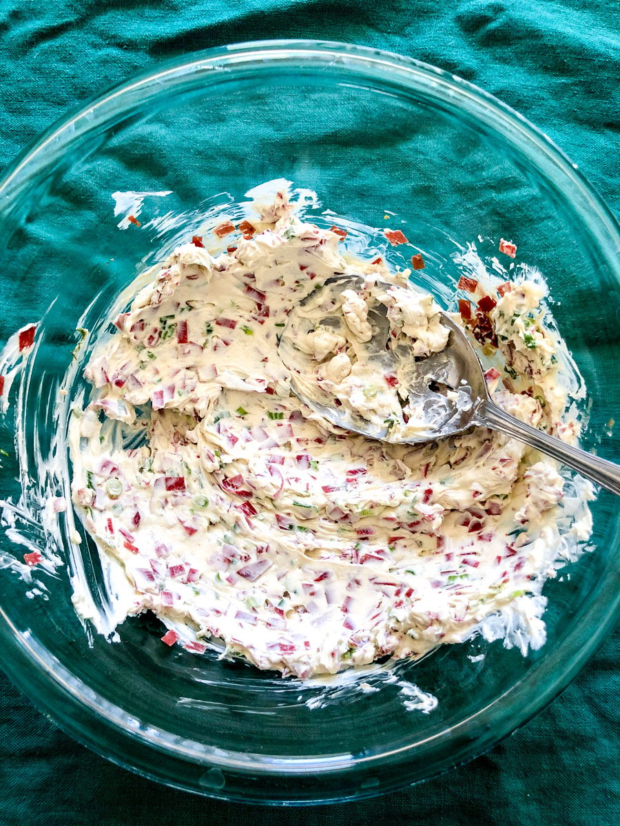 mixed up ingredients for a dried beef cheese ball in a glass bowl.