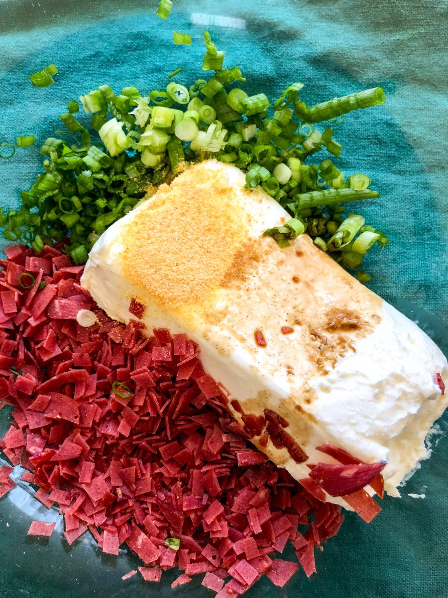 all the ingredients for a dried beef cheese ball in a glass bowl.