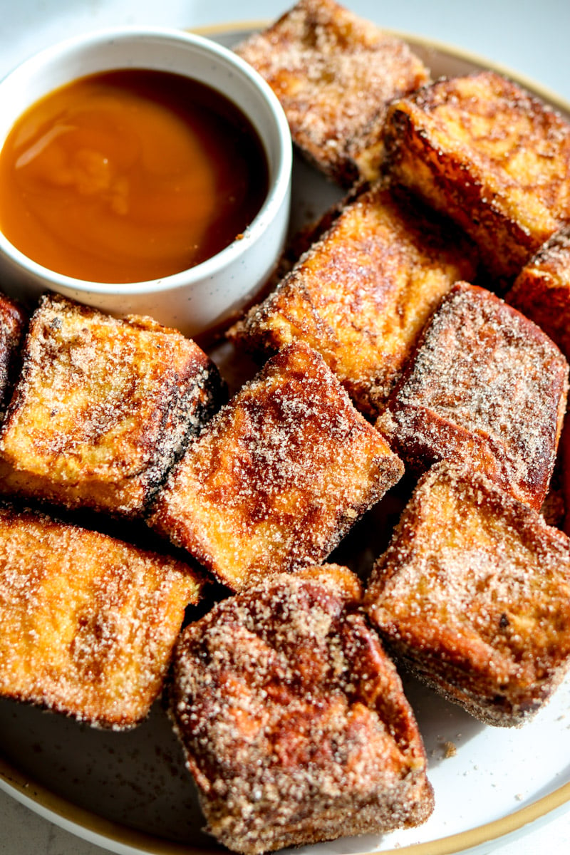 a white plate filled up with hawaiian roll french toast bites.