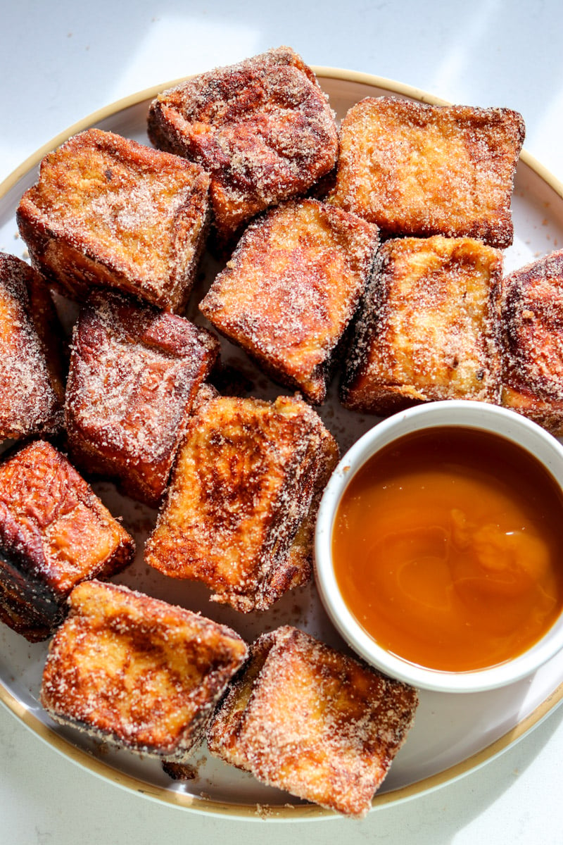 a white plate of hawaiian roll french toast bites.