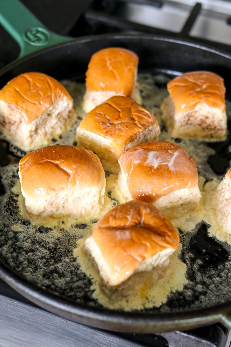 hawaiian rolls cooking in melted butter in a large nonstick skillet.