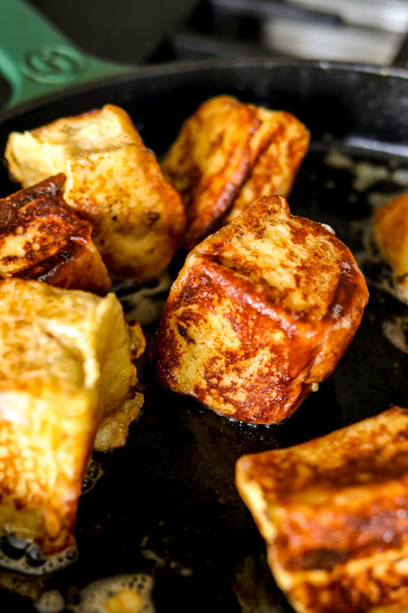 golden brown hawaiian roll french toast with crisp edges in a nonstick skillet. 