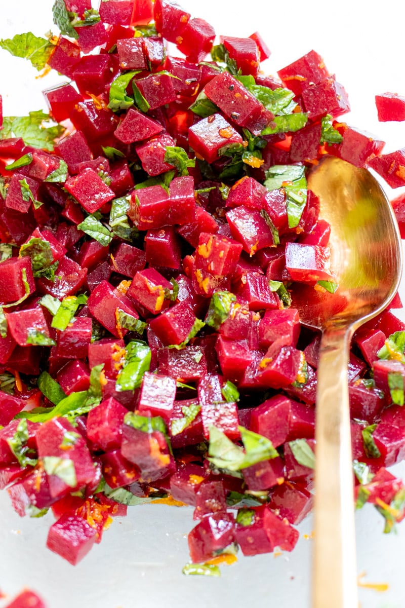 marinated pickled beets ini a glass bowl with a golden spoon.