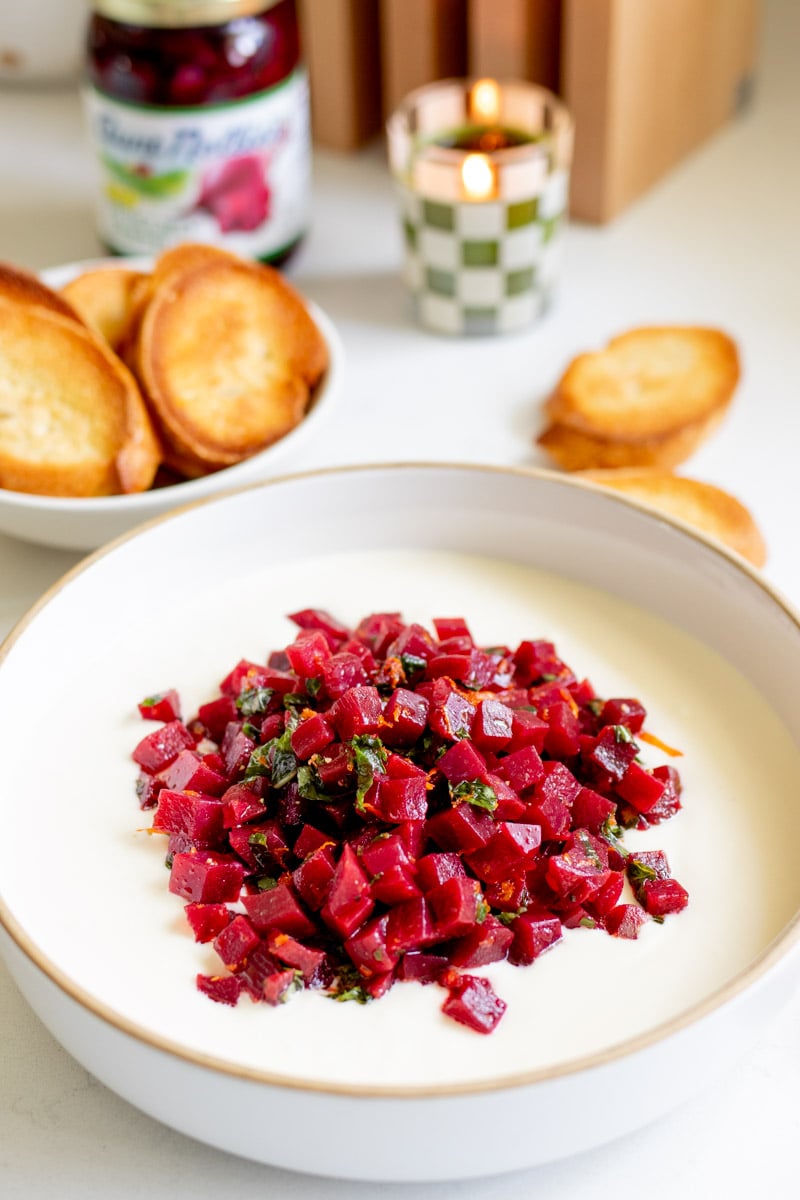 a white bowl filled with white whipped feta and bright pink pickled beet salad.