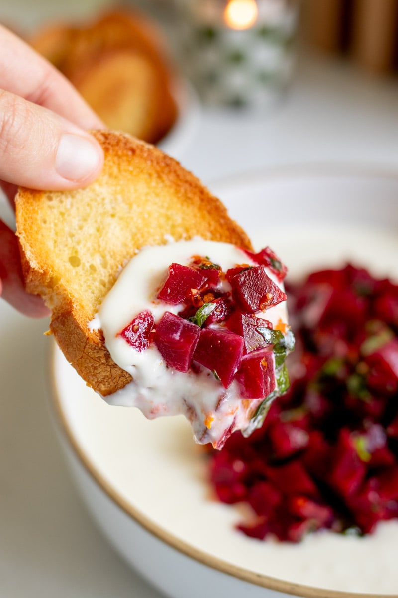 a piece of toasted baguette after being dunked in the hot honey whipped feta.