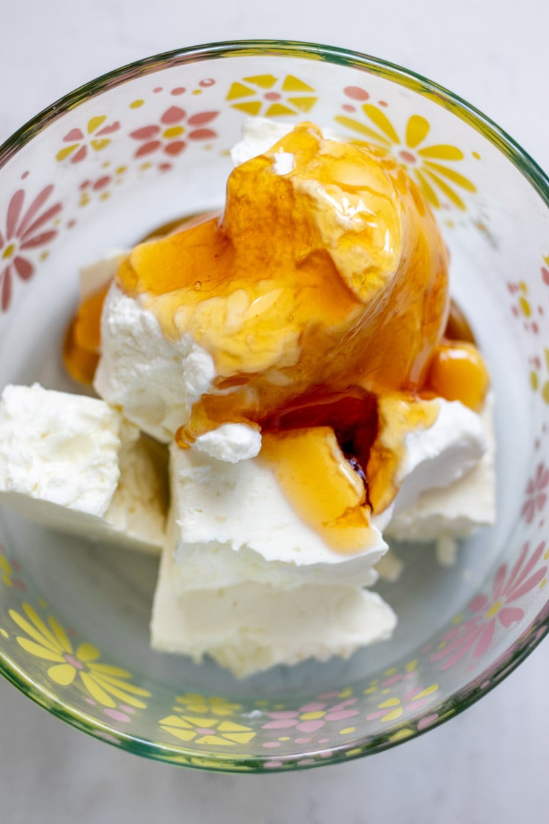 feta topped with greek yogurt and hot honey in a glass bowl.