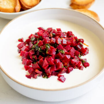 a white bowl filled with hot honey whipped feta and a vibrant pickled beets salad.