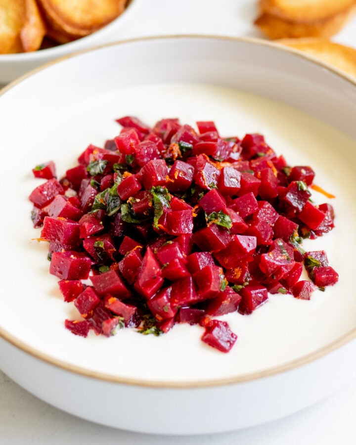 a white bowl filled with hot honey whipped feta and a vibrant pickled beets salad.