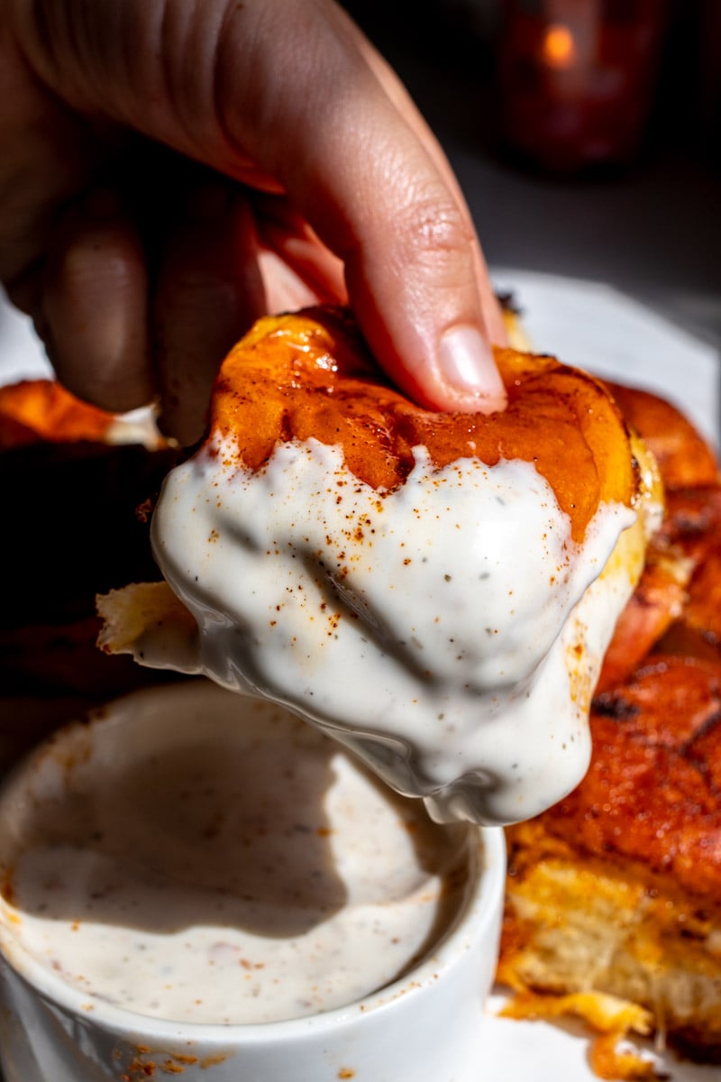 a hand holding a nashville hot mozzarella slider after it's been dunked in ranch dressing. 