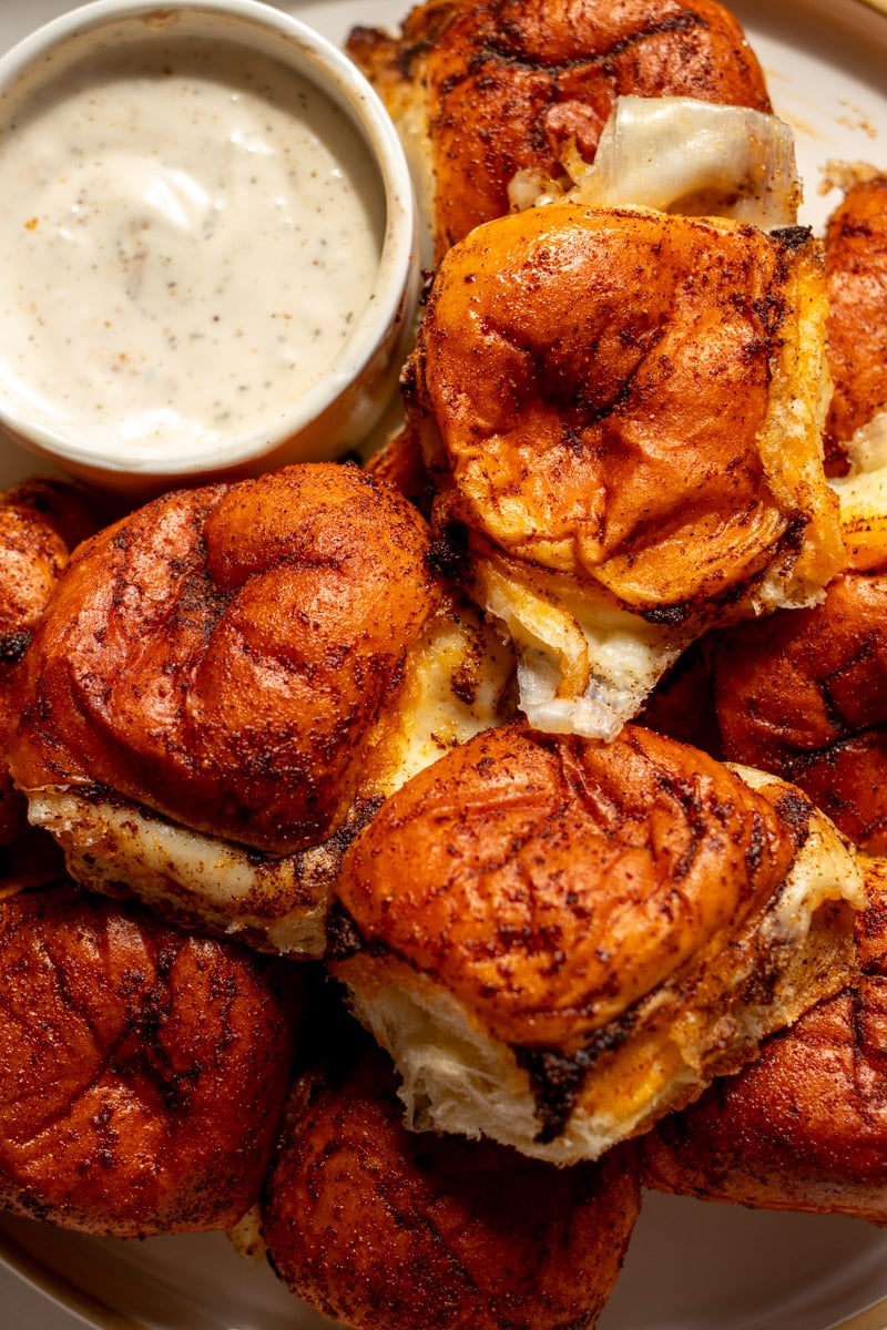 a platter full of nashville hot mozzarella sliders with a small white bowl full of ranch dressing.