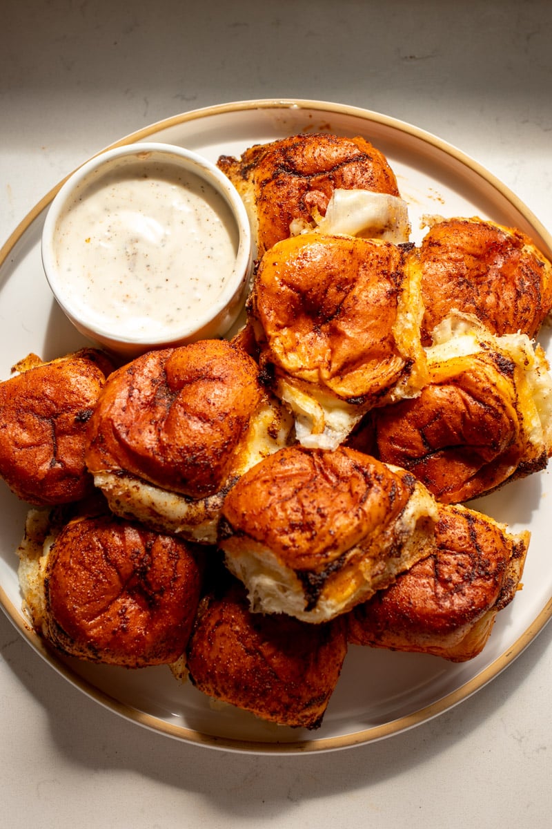 an overhead view of a platter of nashville hot mozzarella sliders with a side of ranch dressing.