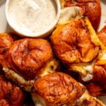 a platter full of nashville hot mozzarella sliders with a small white bowl full of ranch dressing.