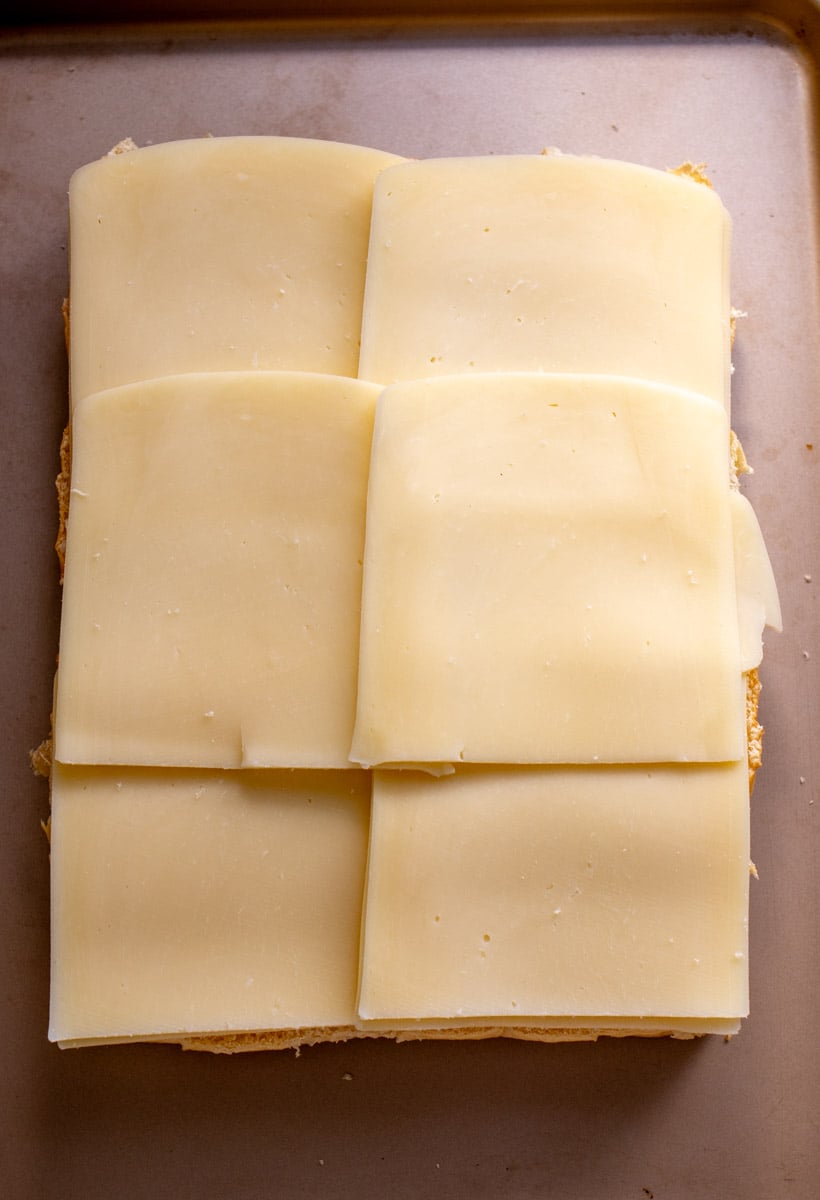  slices of mozzarella cheese on a half of a pack of kings hawaiian rolls. 