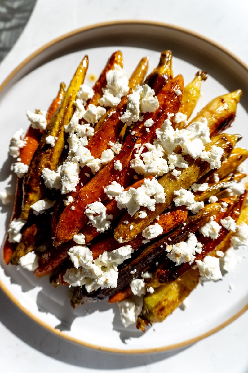 carrots topped with goat cheese on a white plate.