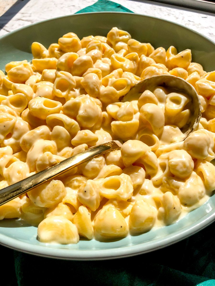 a side angle of a blue bowl filled with mac and cheese.