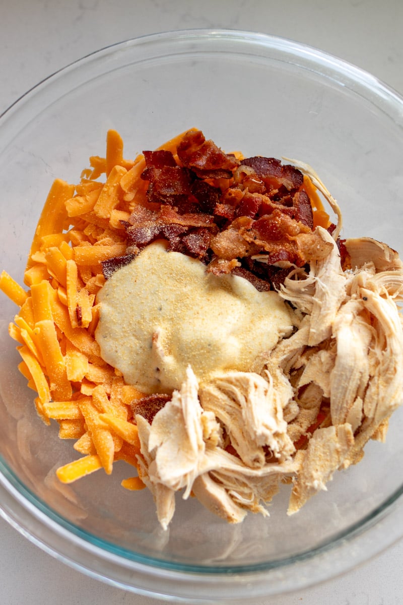 all the ingredients for a chicken bacon ranch grilled cheese in a glass bowl.