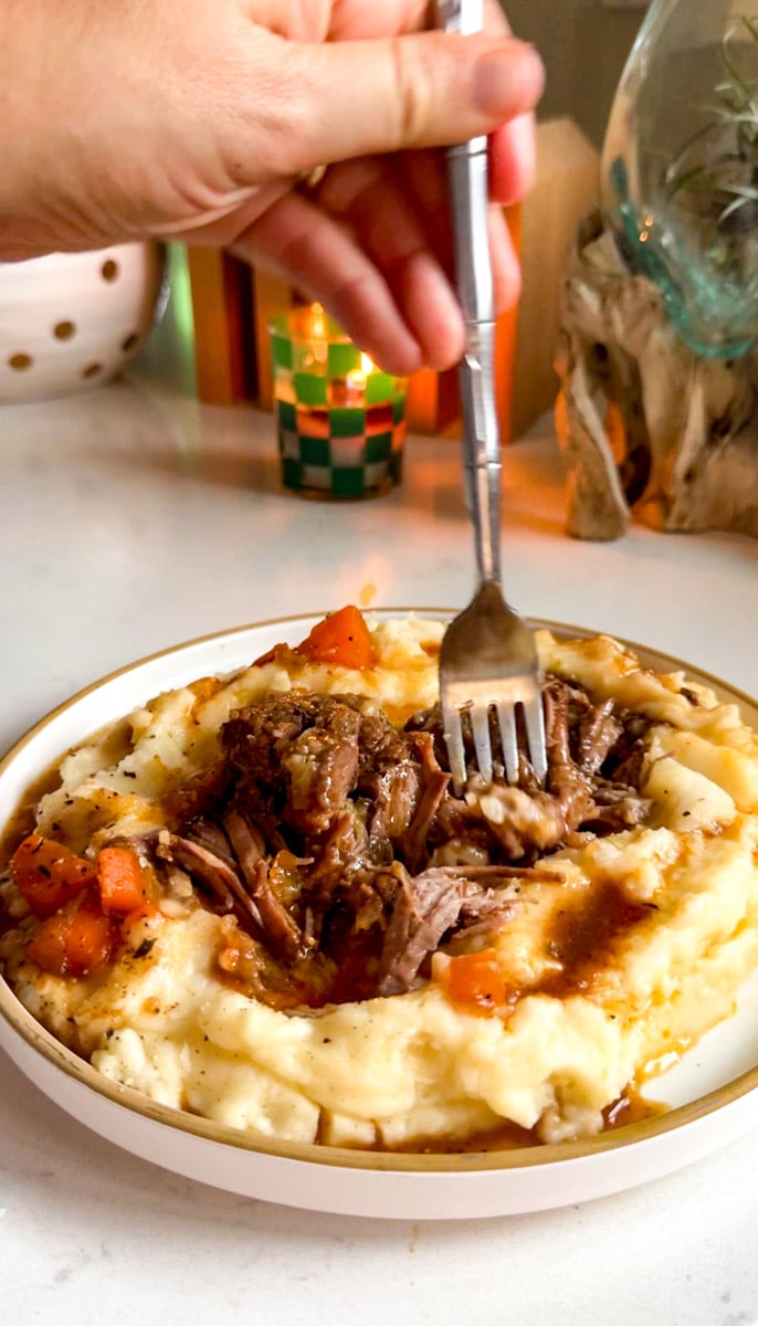 a fork digging into a plate of chuck short ribs.