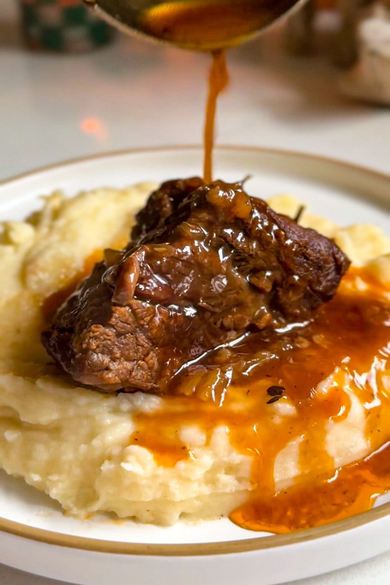 an up close view of a short rib with gravy being poured on top.