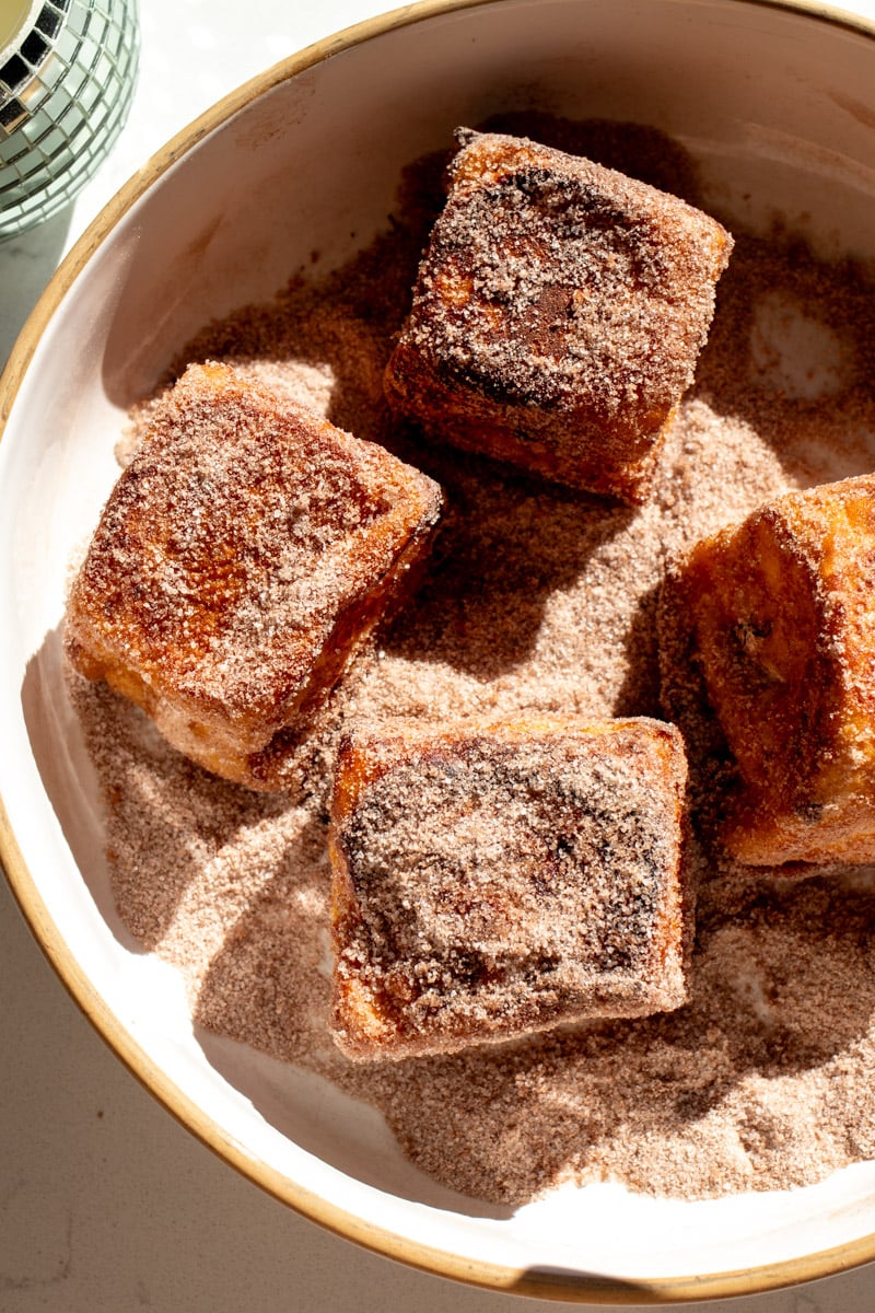 hote chocolate french toast bites being rolled in hot chocolate sugar.