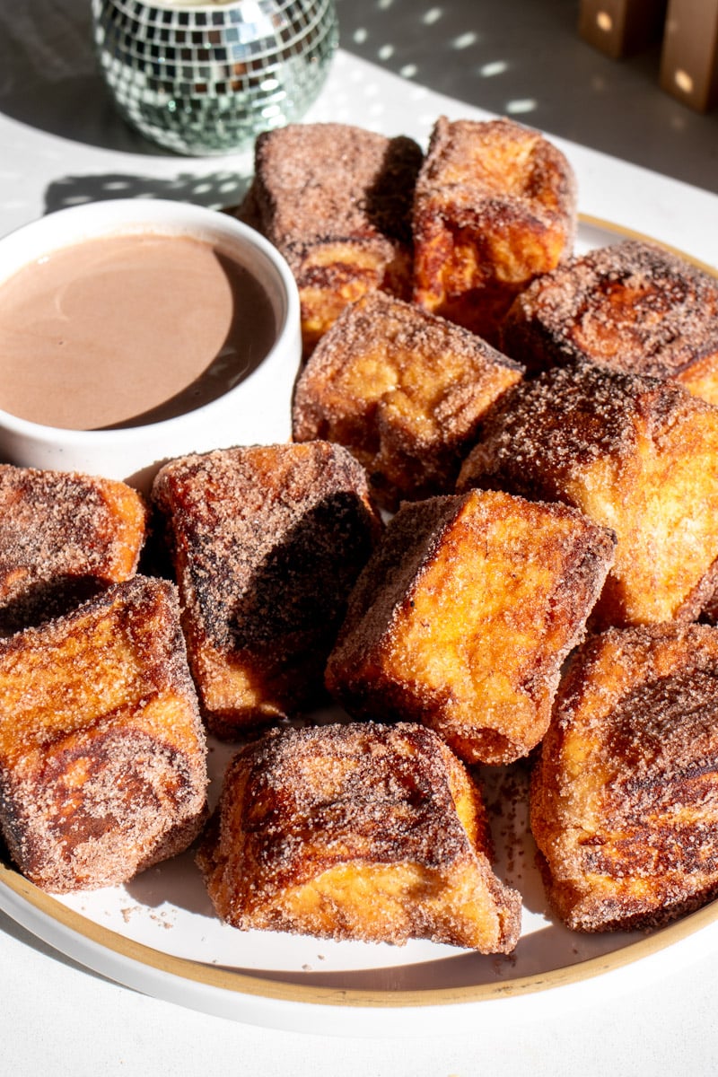 a white plate of hot cocoa french toast bites with a hot chocolate dipping sauce. 