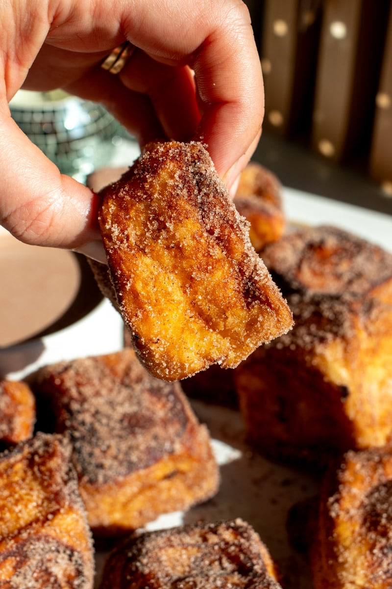 a hand holding a hot chocolate french toast bite.