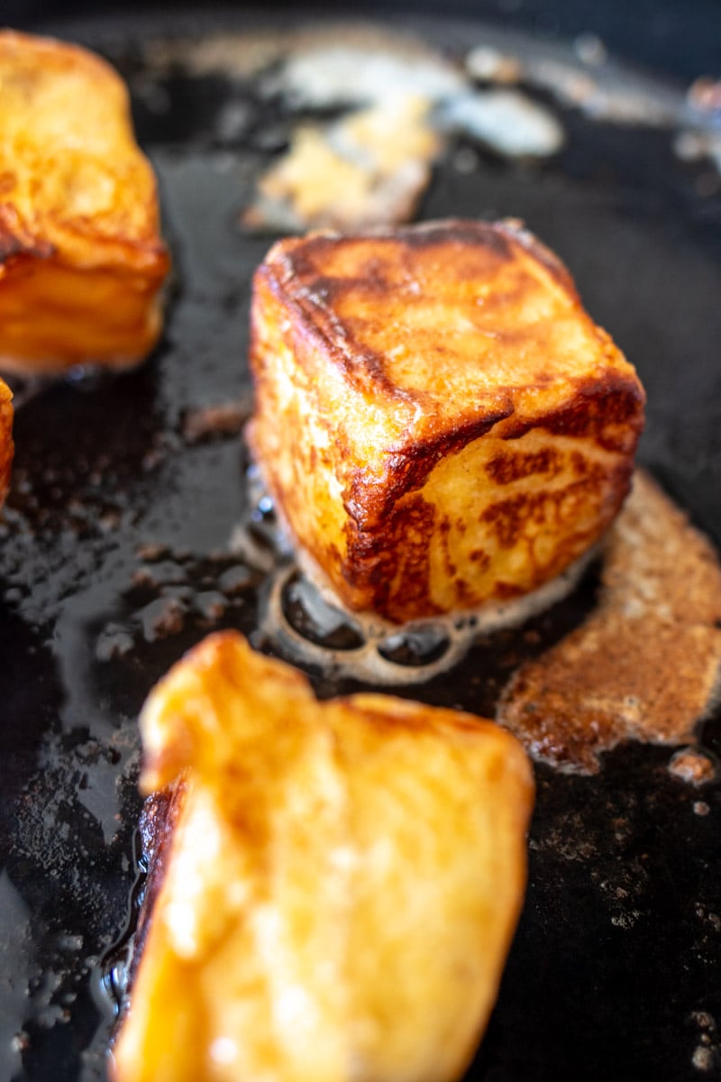 a frying pan full of french toast bites getting crispy with melted butter.