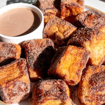 a white plate of hot cocoa french toast bites with a hot chocolate dipping sauce.