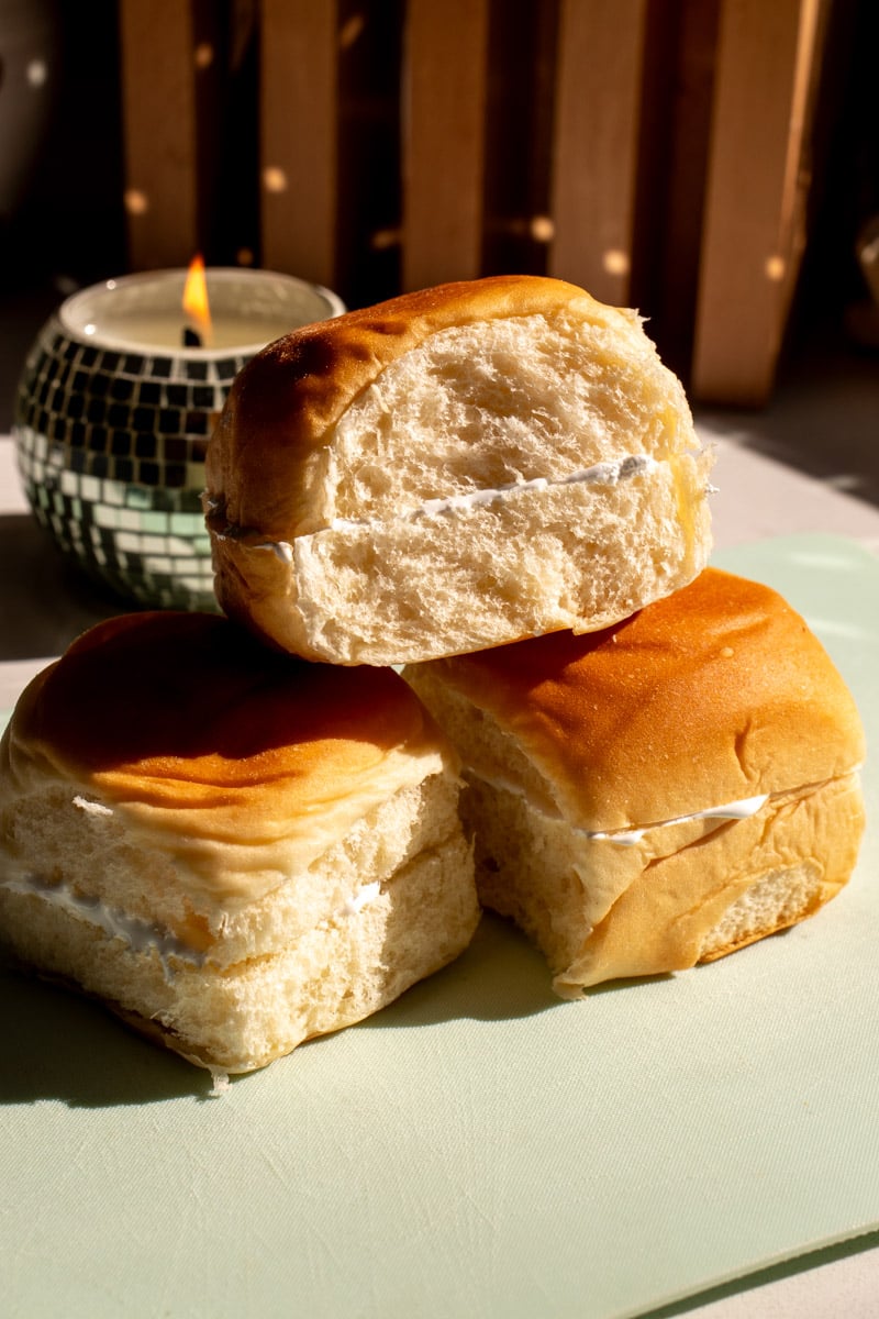 kings hawaiian rolls stuffed with marshmallow fluff on a teal cutting board.