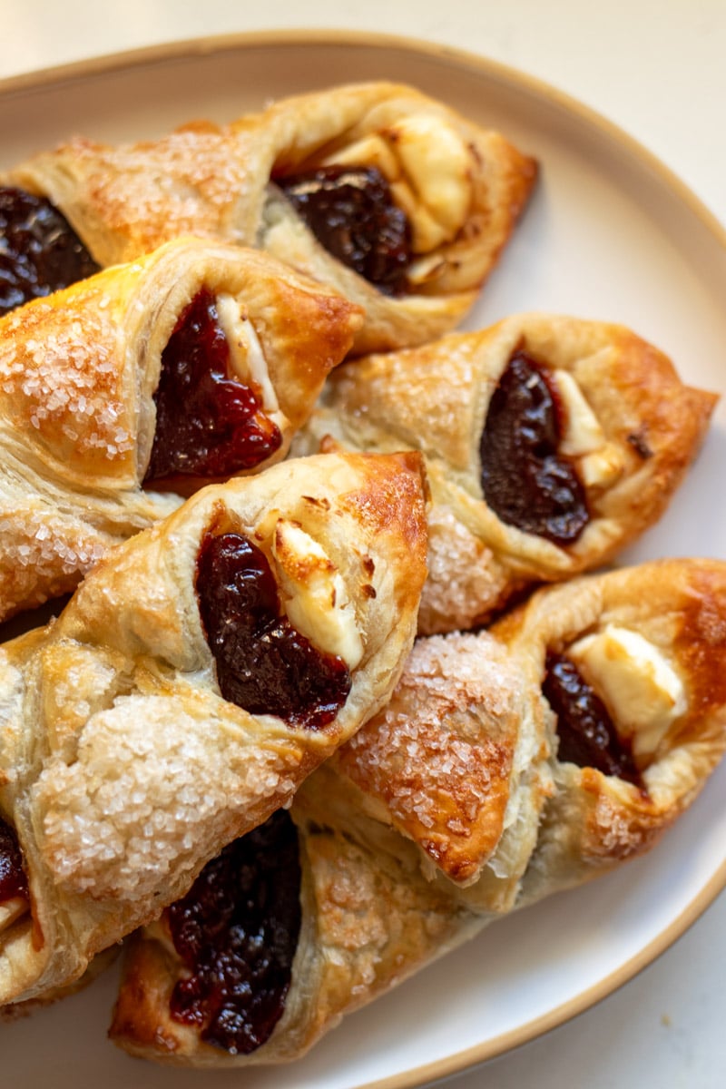 a bunch of guava cream cheese pastelitos on a white serving platter.